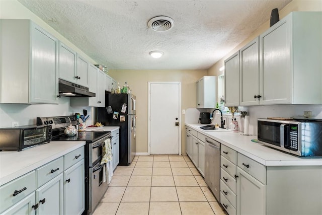 709 W Hughbert St, Norman, OK 73069 - kitchen with appliances with stainless steel finishes, under cabinet range hood, light countertops, light tile patterned flooring, and a textured ceiling