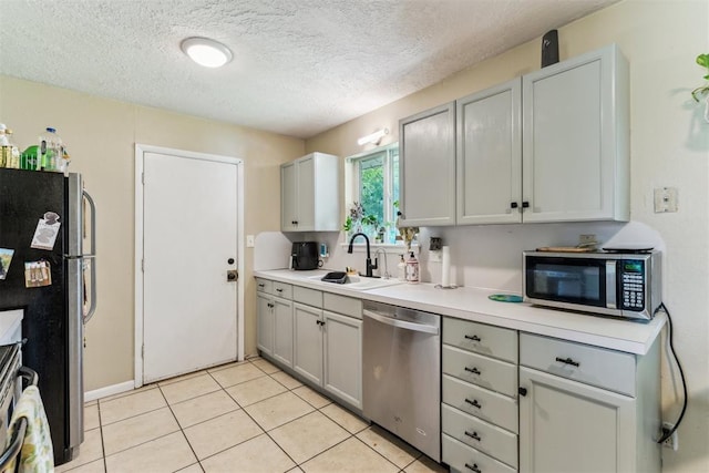 709 W Hughbert St, Norman, OK 73069 - kitchen with stainless steel appliances, light countertops, a textured ceiling, light tile patterned flooring, and gray cabinets