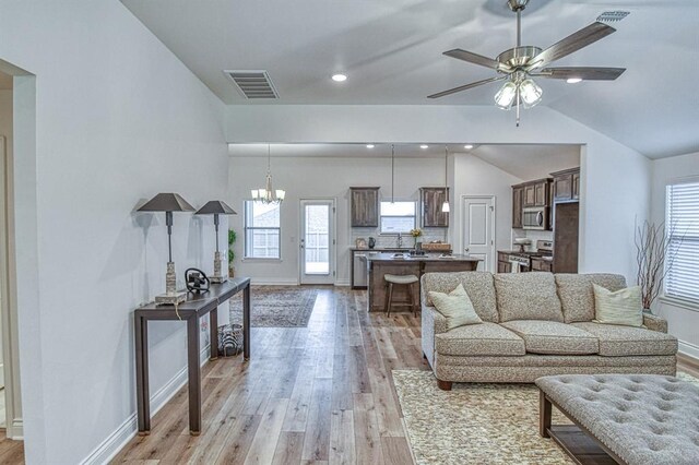 12712 NW 4th St, Yukon, OK 73099 - living room with vaulted ceiling, light wood finished floors, plenty of natural light, a ceiling fan, and a chandelier