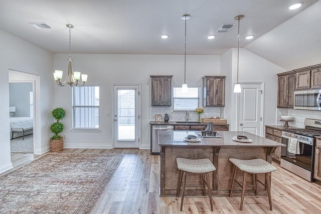 12712 NW 4th St, Yukon, OK 73099 - kitchen with appliances with stainless steel finishes, a kitchen bar, light wood-type flooring, a chandelier, and backsplash