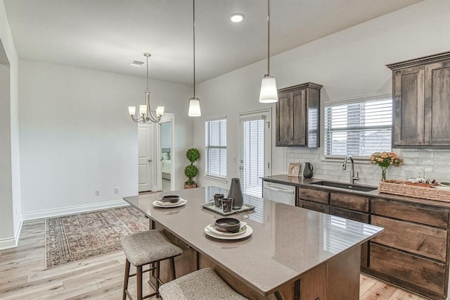 12712 NW 4th St, Yukon, OK 73099 - kitchen featuring dishwasher, light wood-type flooring, decorative backsplash, a kitchen island, and dark brown cabinets