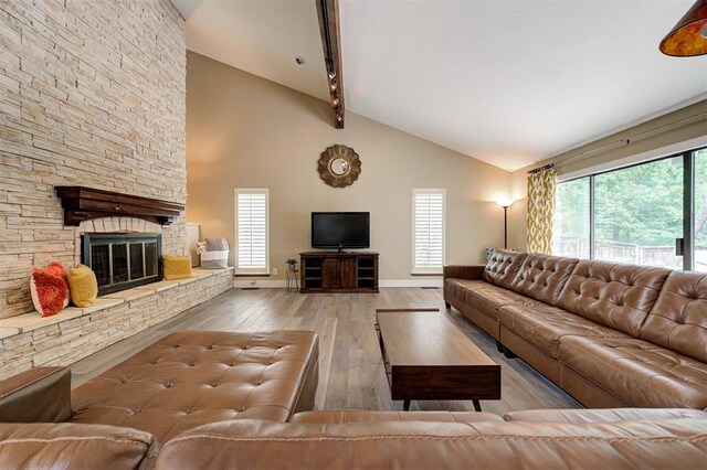 1810 Sandpiper Dr, Edmond, OK 73034 - living area featuring hardwood / wood-style floors, beamed ceiling, high vaulted ceiling, and a stone fireplace