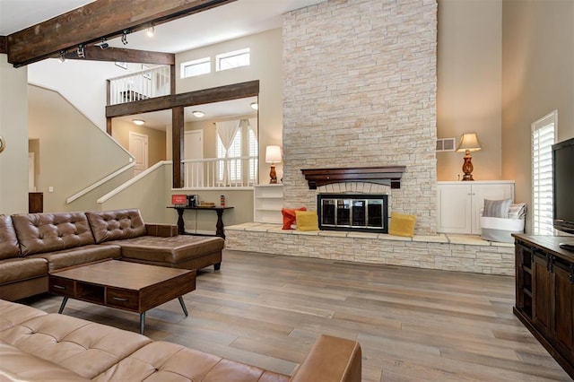 1810 Sandpiper Dr, Edmond, OK 73034 - living room with a high ceiling, healthy amount of natural light, wood finished floors, rail lighting, and a stone fireplace