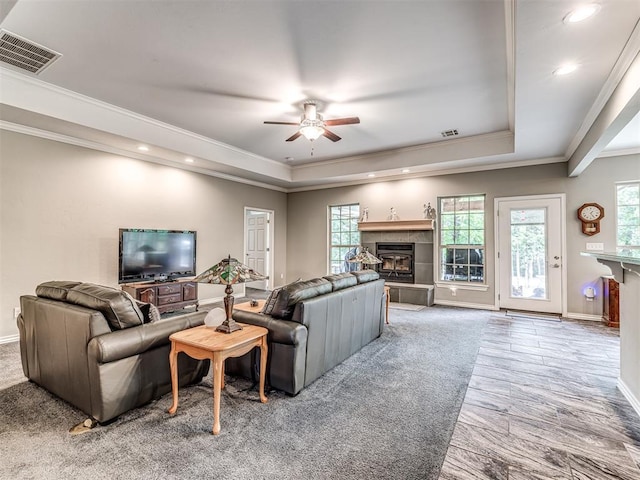 940908 S 3300th Rd, Luther, OK 73054 - living room featuring a tray ceiling, a tiled fireplace, ceiling fan, ornamental molding, and recessed lighting
