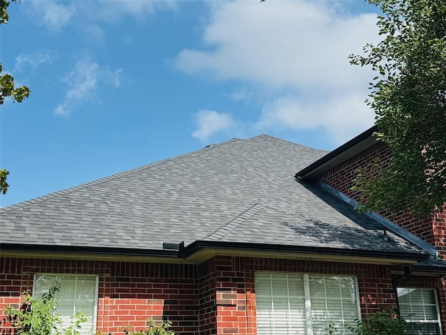 exterior view of a shingled roof and brick siding