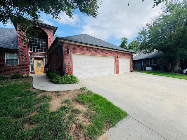 traditional-style home with brick siding, driveway, an attached garage, and a shingled roof