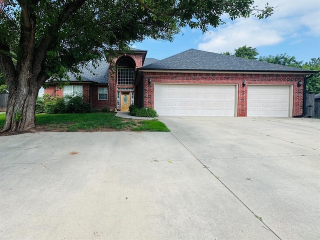 traditional-style house featuring driveway, brick siding, an attached garage, and a shingled roof