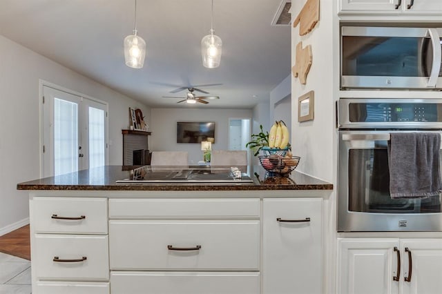 4813 NW 65th St, Oklahoma City, OK 73132 - kitchen featuring stainless steel appliances, ceiling fan, a fireplace, white cabinets, and hanging light fixtures