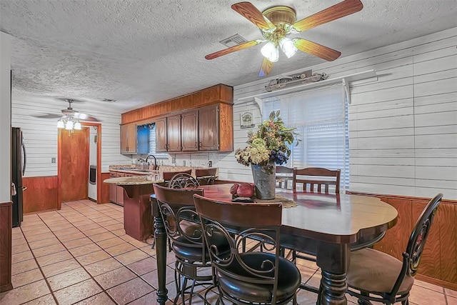 1108 S 13th St, Clinton, OK 73601 - dining space with a ceiling fan, wood walls, a textured ceiling, and light tile patterned floors