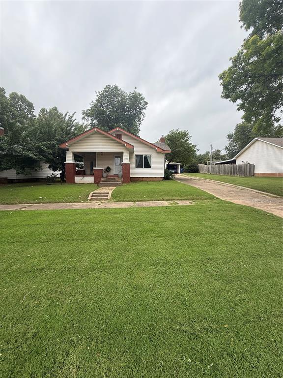 1522 S 9th St, Chickasha, OK 73018 - view of front facade with concrete driveway, a front yard, and covered porch