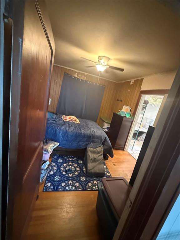 1522 S 9th St, Chickasha, OK 73018 - bedroom featuring wood finished floors, wooden walls, and a ceiling fan