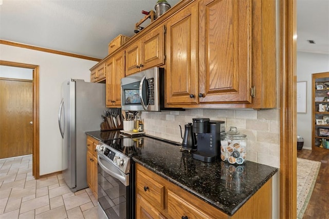 5 Larkens Pl, Shawnee, OK 74801 - kitchen with appliances with stainless steel finishes, brown cabinets, tasteful backsplash, crown molding, and dark stone countertops