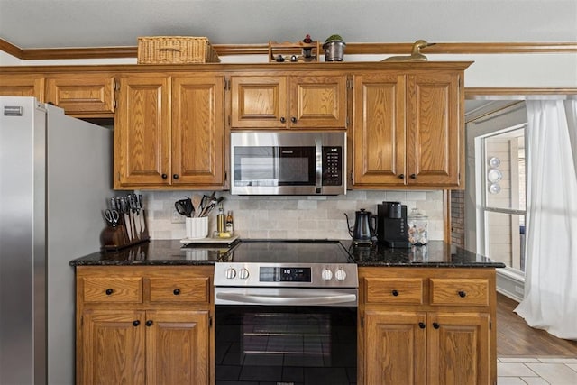 5 Larkens Pl, Shawnee, OK 74801 - kitchen featuring appliances with stainless steel finishes, crown molding, decorative backsplash, brown cabinets, and dark stone countertops