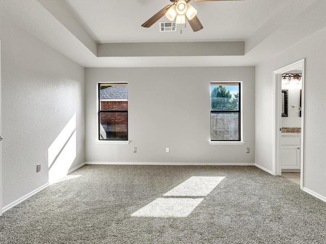 4001 Tori Pl, Yukon, OK 73099 - unfurnished bedroom with carpet floors, a tray ceiling, ensuite bath, and ceiling fan