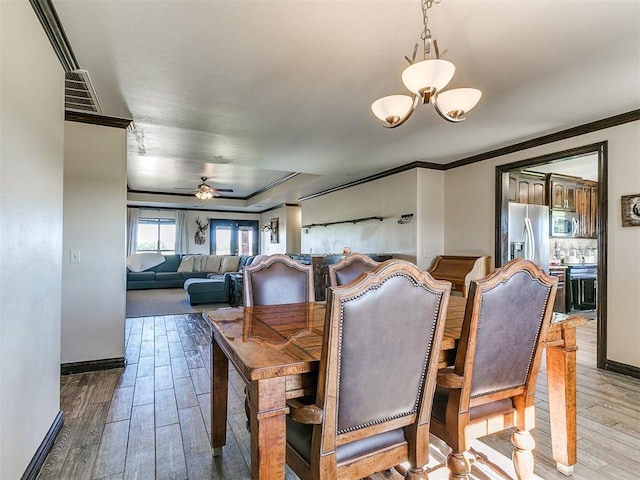 5053 Northridge Run, Cashion, OK 73016 - dining room featuring crown molding, wood finished floors, ceiling fan, and a chandelier