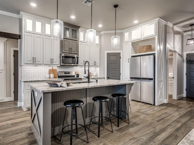 11716 SW 47th St, Mustang, OK 73064 - kitchen featuring appliances with stainless steel finishes, ornamental molding, wood finished floors, backsplash, and light stone counters