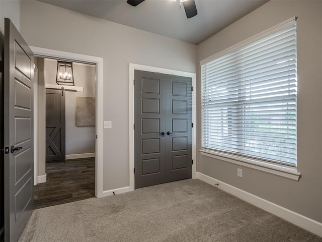 11716 SW 47th St, Mustang, OK 73064 - unfurnished bedroom with a barn door, dark colored carpet, and ceiling fan
