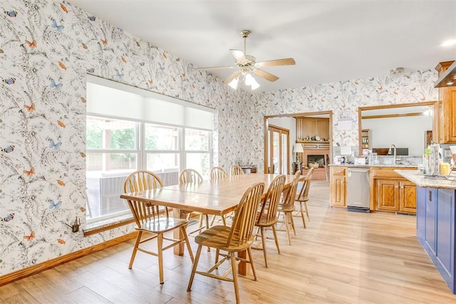 11748 SW 54th St, Mustang, OK 73064 - dining space featuring wallpapered walls, a ceiling fan, light wood finished floors, and a fireplace