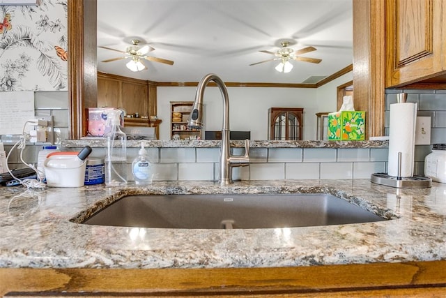 11748 SW 54th St, Mustang, OK 73064 - kitchen with ornamental molding, light stone counters, a ceiling fan, and brown cabinets