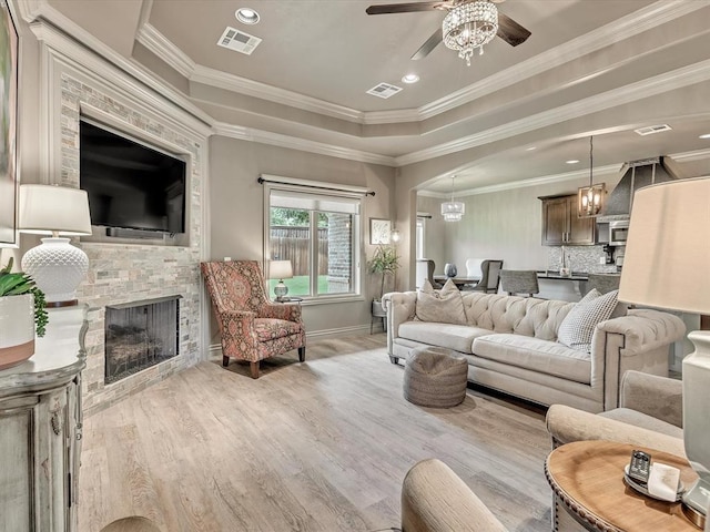 16117 Cale Dr, Edmond, OK 73013 - living room featuring ceiling fan, crown molding, a stone fireplace, arched walkways, and wood finished floors