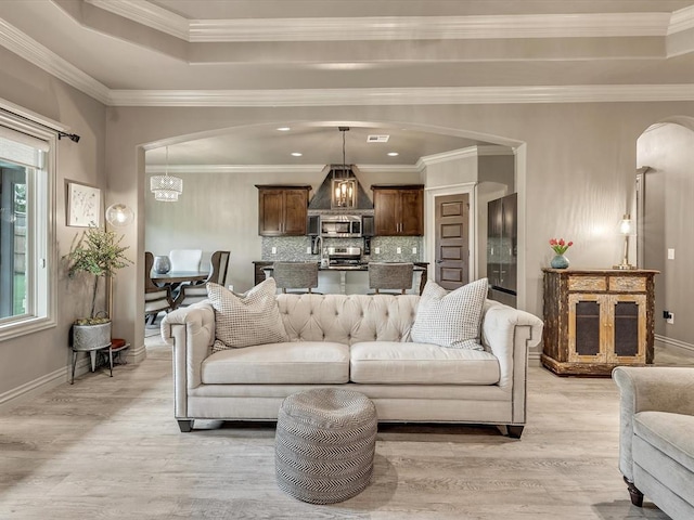 16117 Cale Dr, Edmond, OK 73013 - living room featuring arched walkways, light wood-type flooring, crown molding, and a chandelier