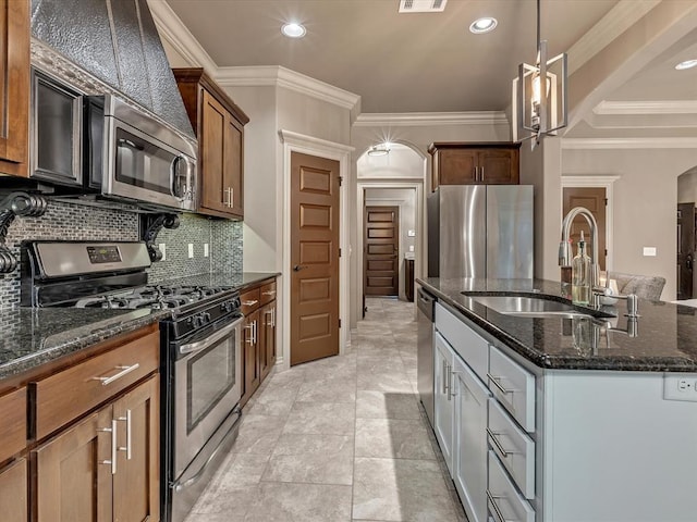 16117 Cale Dr, Edmond, OK 73013 - kitchen with stainless steel appliances, crown molding, a center island with sink, dark stone countertops, and backsplash