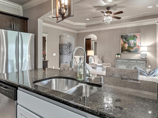 16117 Cale Dr, Edmond, OK 73013 - kitchen with arched walkways, ceiling fan, dark stone counters, dark brown cabinets, and crown molding