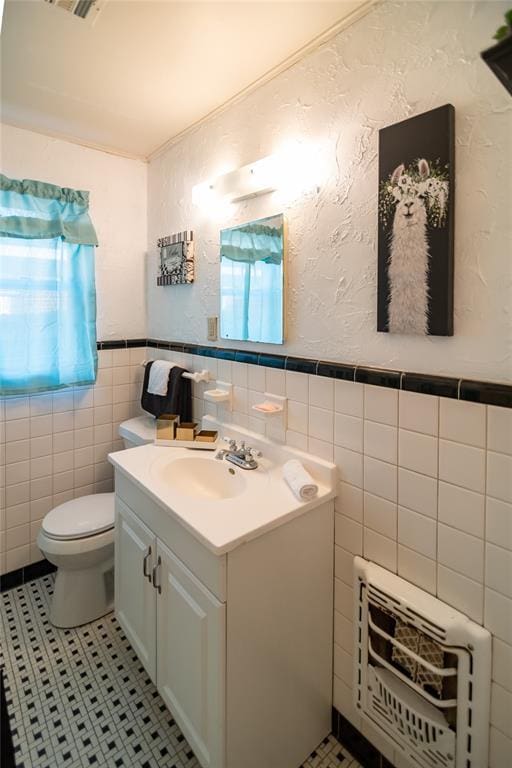 4117 NW 21st St, Oklahoma City, OK 73107 - half bath with tile walls, heating unit, vanity, tile patterned flooring, and a wainscoted wall