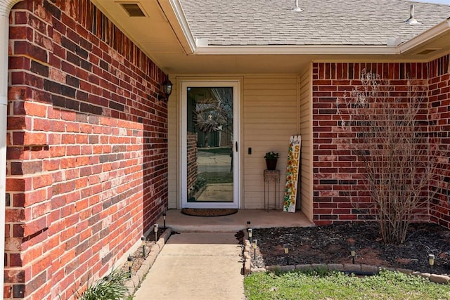 21854 Meadow Mist Cir, Edmond, OK 73012 - view of exterior entry featuring roof with shingles and brick siding