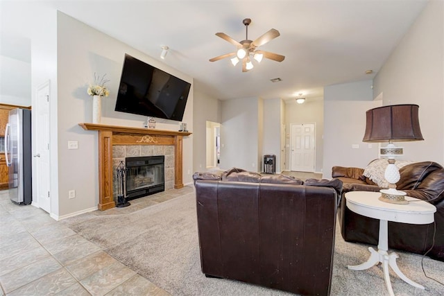 21854 Meadow Mist Cir, Edmond, OK 73012 - living area featuring a ceiling fan, a fireplace, light tile patterned floors, and light colored carpet