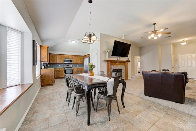 21854 Meadow Mist Cir, Edmond, OK 73012 - dining room with vaulted ceiling, ceiling fan, a fireplace, and a chandelier