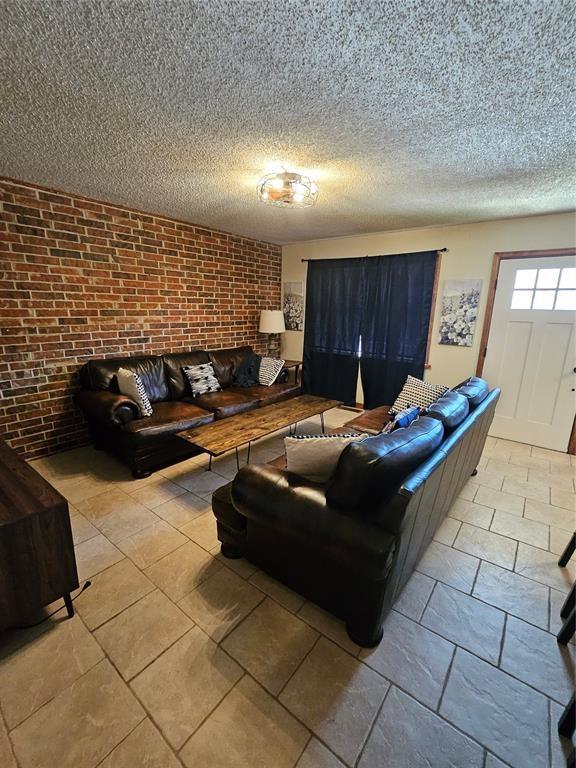 321 W 4th St, Hobart, OK 73651 - living area featuring brick wall and a textured ceiling