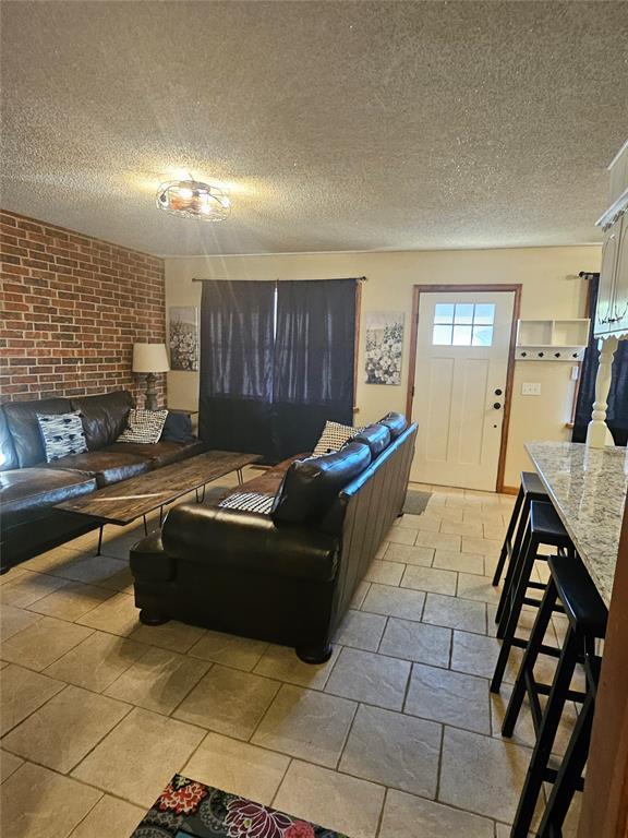 321 W 4th St, Hobart, OK 73651 - living room with a textured ceiling and brick wall