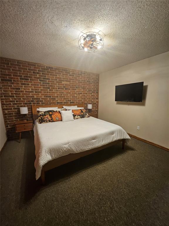 321 W 4th St, Hobart, OK 73651 - bedroom with carpet floors, a textured ceiling, and brick wall