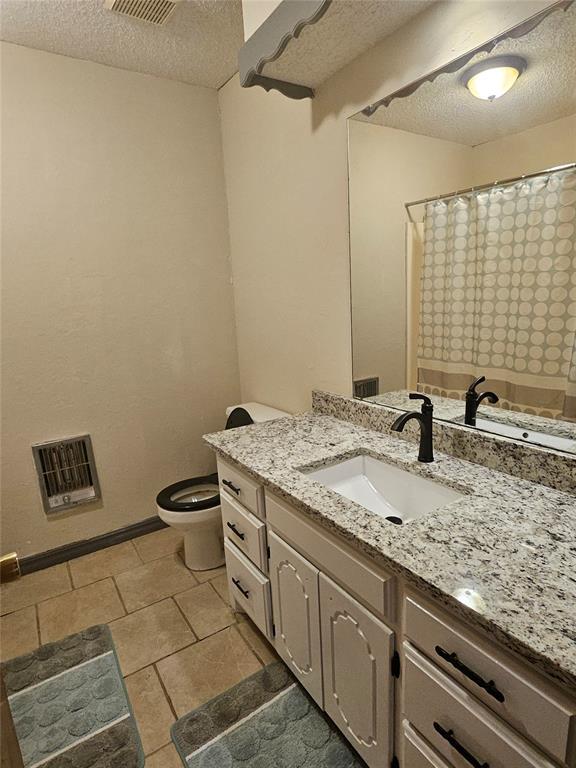321 W 4th St, Hobart, OK 73651 - full bath with a textured ceiling, vanity, heating unit, tile patterned floors, and a shower with curtain