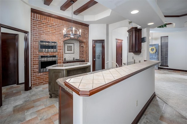 9124 SW 28th St, Oklahoma City, OK 73128 - kitchen featuring stone tile floors, a center island, tile countertops, dark brown cabinetry, and pendant lighting