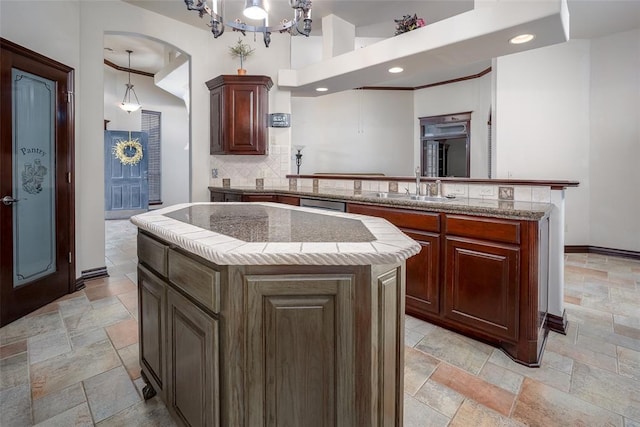 9124 SW 28th St, Oklahoma City, OK 73128 - kitchen featuring stone tile floors, a peninsula, a kitchen island, backsplash, and arched walkways