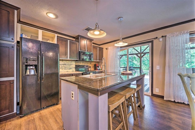 86 Crooked Oaks Ln, Broken Bow, OK 74728 - kitchen featuring black appliances, wood finished floors, tasteful backsplash, dark stone counters, and a kitchen bar