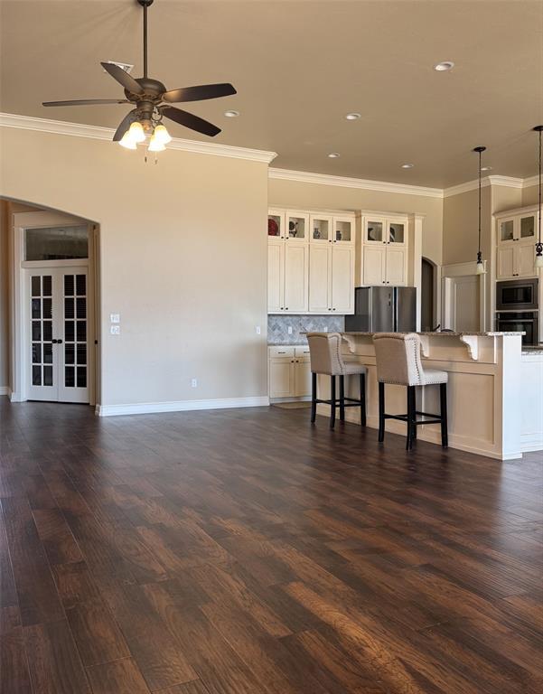 3000 Warwick Pl, Edmond, OK 73013 - kitchen with appliances with stainless steel finishes, crown molding, ceiling fan, a breakfast bar, and glass insert cabinets