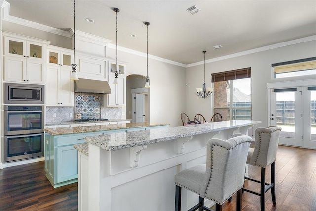 3000 Warwick Pl, Edmond, OK 73013 - kitchen with stainless steel appliances, a center island, extractor fan, dark wood-style floors, and ornamental molding