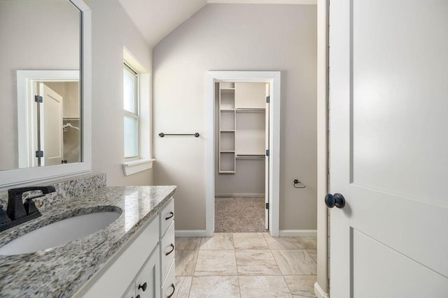 3000 Warwick Pl, Edmond, OK 73013 - bathroom featuring vanity, vaulted ceiling, a spacious closet, and marble look tile flooring