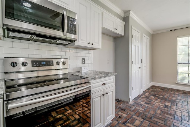 16408 Del Mar Dr, Edmond, OK 73013 - kitchen with appliances with stainless steel finishes, ornamental molding, brick floors, white cabinetry, and backsplash