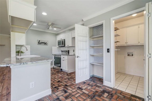 16408 Del Mar Dr, Edmond, OK 73013 - kitchen featuring appliances with stainless steel finishes, a ceiling fan, crown molding, decorative backsplash, and a peninsula
