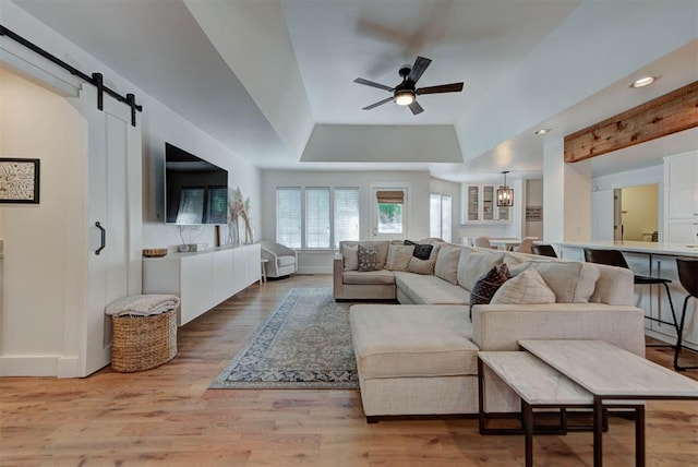 1001 Fountain Gate Cir, Norman, OK 73072 - living area featuring ceiling fan, a barn door, a tray ceiling, light wood-style flooring, and recessed lighting