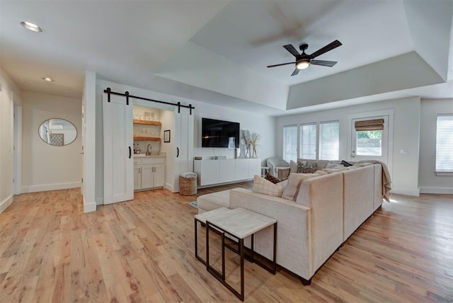 1001 Fountain Gate Cir, Norman, OK 73072 - living area featuring a tray ceiling, a barn door, a ceiling fan, light wood-style floors, and recessed lighting