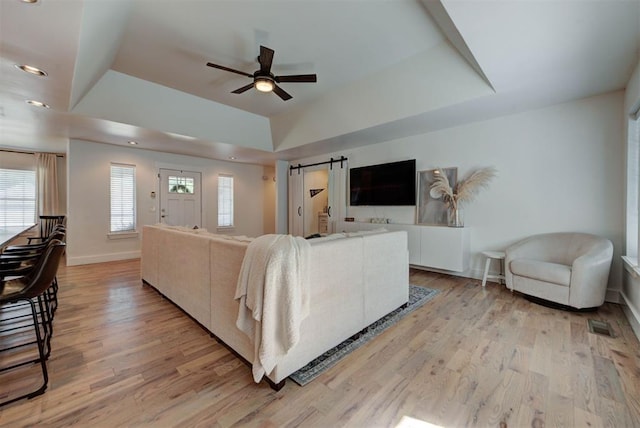 1001 Fountain Gate Cir, Norman, OK 73072 - living area with a barn door, a raised ceiling, a ceiling fan, light wood-style flooring, and recessed lighting