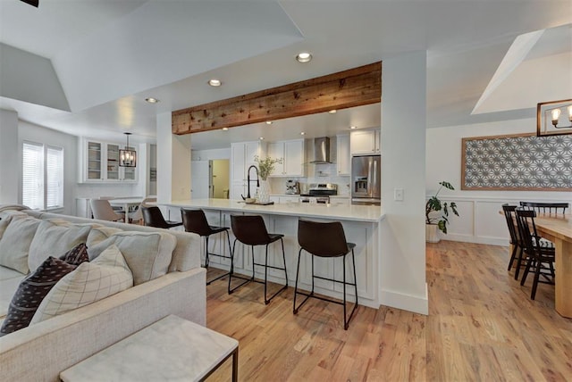 1001 Fountain Gate Cir, Norman, OK 73072 - kitchen with appliances with stainless steel finishes, wall chimney exhaust hood, a kitchen breakfast bar, open floor plan, and light wood-type flooring