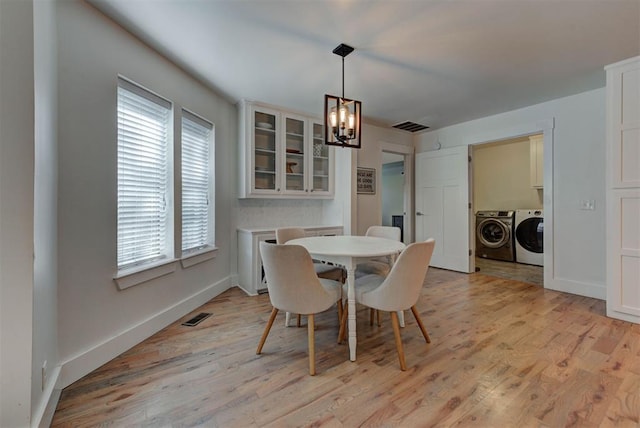 1001 Fountain Gate Cir, Norman, OK 73072 - dining room featuring independent washer and dryer, a chandelier, plenty of natural light, and light wood-style floors