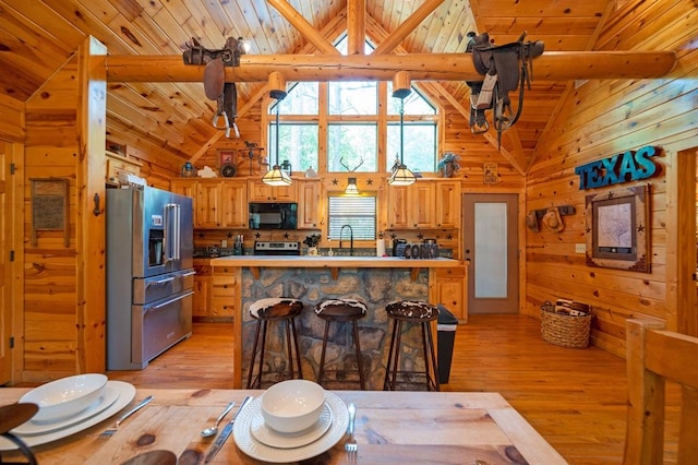 244 Hiddenwater Rd, Broken Bow, OK 74728 - kitchen with stainless steel appliances, light wood-type flooring, high vaulted ceiling, wooden walls, and a breakfast bar area