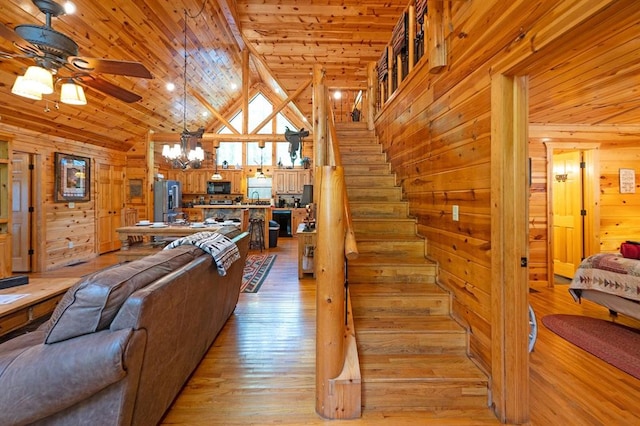 244 Hiddenwater Rd, Broken Bow, OK 74728 - living room with wood walls, a ceiling fan, a wood ceiling with exposed beams, light wood-style floors, and a chandelier